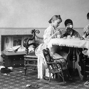 Four girls having a tea party around a table. Photograph, c1893