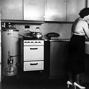 HOMESTEAD KITCHEN, 1936. Homesteader washing dishes in the kitchen of her new home