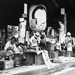 A makeshift food market at the gate of a Buddhist temple in or near Tokyo, Japan, in the aftermath of the great earthquake that struck the Kanto plain on 1 September 1923. Columns and a large lantern are covered with posters sharing and seeking information about people