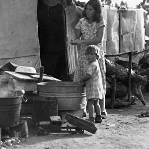 MIGRANT WORKER CAMP, 1935. Mother and child using a wash basin in a rehabilitation