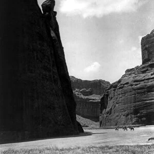 NAVAJOS IN CANYON, c1906. Three Navajos riding on horseback dwarfed by canyon walls