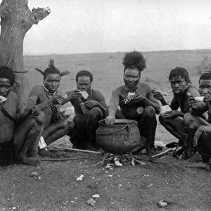 SOUTH AFRICA: ZULU MEN. Zulu men seated on the ground while eating from a large pot, South Africa
