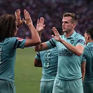 Arsenal's Unstoppable Moment: Holding and Guendouzi Celebrate Goal Against Paris Saint-Germain