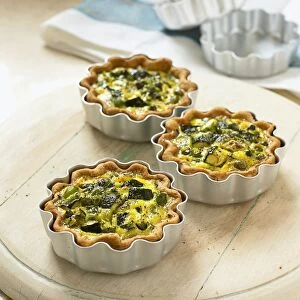 Three baked courgette quiches in tins