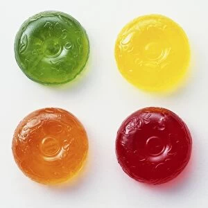 Four boiled sweets coloured green, yellow, orange and red