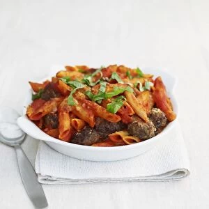Bowl of penne pasta with meatballs and basil
