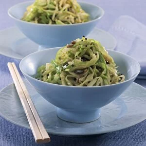 Bowls of vermicelli noodles with sauteed cabbage and toasted seeds, chopsticks, close-up