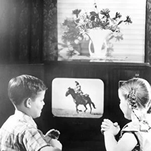 Boy and girl watching cowboy on television