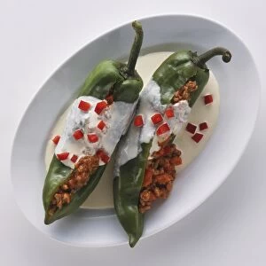 Chiles en nogada, two green chillis stuffed with ground meat and almonds, covered in walnut sauce and garnished with pomegranate kernels