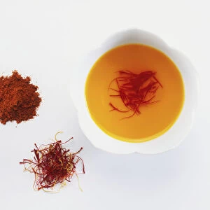 Crocus sativus, Saffron threads, raw, being soaked in a bowl and powdered