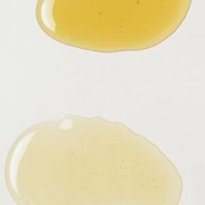 A droplet of yellow oil beside a droplet of colourless oil