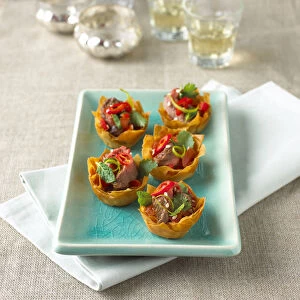 Filo pastry filled with Asian beef salad and garnished with peppers, coriander leaves and sesame seeds