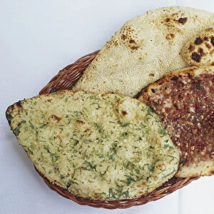 Garlic naan, plain naan, and mint naan, tandoori-style Indian breads, served in basket