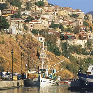 Greece, Lesvos, Molyvos, tiered stone houses rising above picturesque harbour, fishing boats moored in foreground