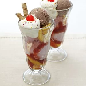 Knickerbocker Glory, ice cream, peaches and whipped cream, garnished with cherries and wafer biscuits, served in two glasses, close-up
