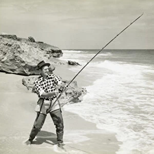 Man fishing in ocean from beach, black and white