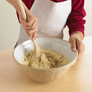 Man mixing cake batter with wooden spoon