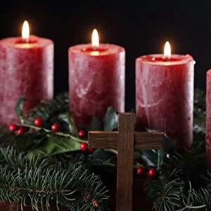 Natural advent wreath or crown with four burning red candles and christian cross