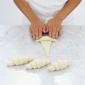 Puff pastry being rolled to create croissants, high angle view