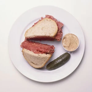 Rye bread sandwich stuffed with corned beef, served with mustard and gherkin, a typical New York deli dish, view from above