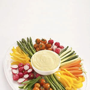 Selection of vegetables, including asparagus, radishes, cherry tomatoes, carrots and cucumbers, arranged around bowl of aioli garlic sauce, high angle view