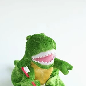 Soft toy dinosaur, holding toothbrush