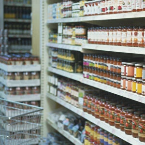 Supermarket shelves containing bottles of organic sauces, tinned vegetables and other goods