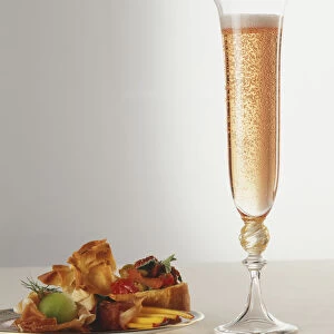 A tall glass of champagne and a plate of canapes
