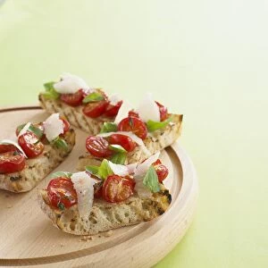 Tomato bruschetta with parmesan shavings and basil leaves, on chopping board, close-up