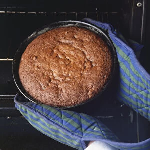 Using kitchen gloves to remove a cake from the oven