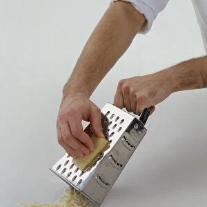 Using metal grater to grate gruyere cheese