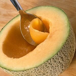Using spoon to scoop out flesh from cantaloupe melon, close-up