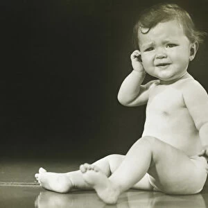 Baby girl (9-12 months) sitting on floor in studio, (B&W)