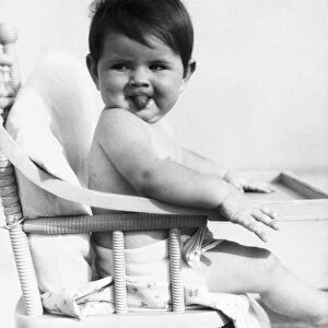 Baby sitting in high chair, sticking out tongue. (Photo by H. Armstrong Roberts / Retrofile / Getty Images)