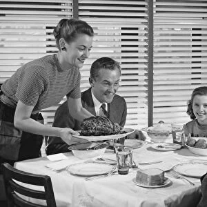 Family dinner, mother holding platter with roast on it