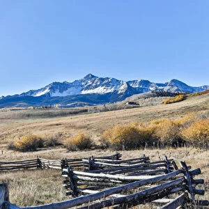 Fence along field and snow-capped San Juan Mountains, Ridgway, Colorado, USA