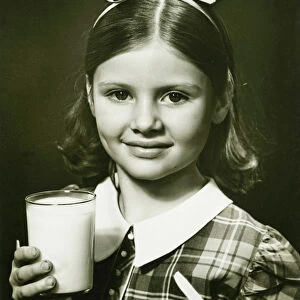 Girl (6-7) holding glass of milk, posing in studio, (B&W), close-up, portrait