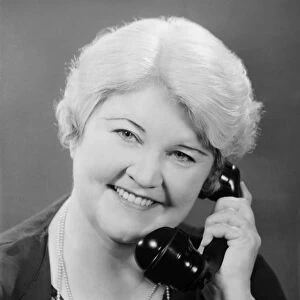 Well groomed mature woman talking on phone, (B&W), close-up, portrait