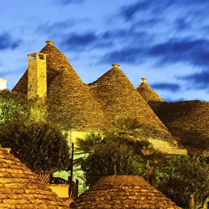 Italy, Apulia, Alberobello, Traditional roofs of trulli houses at sunset