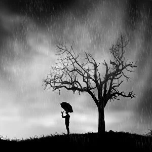 Lonely man with umbrella underneath tree