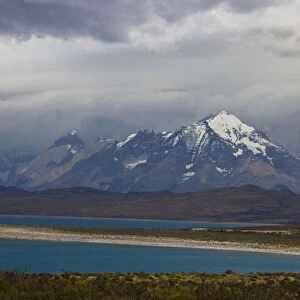 Looking across the turquoise waters of Lake Sarmiento to the snow-capped mountain peaks of the Torres del Paine National Park in the Magallanes Region of Patagonia, Southern Chile