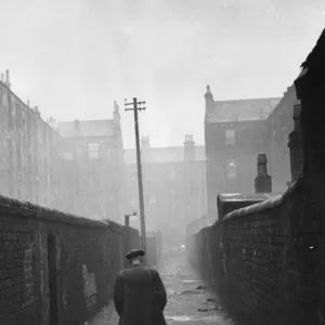 A man walking through a backstreet of the Gorbals area of Glasgow