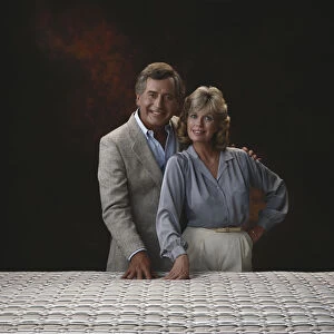 Mature couple standing against black background, smiling, portrait