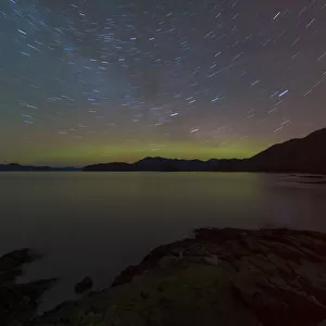 Northern Lights glowing on horizon with star trails, Settlers Cove State Park, Ketchikan, Alaska, USA