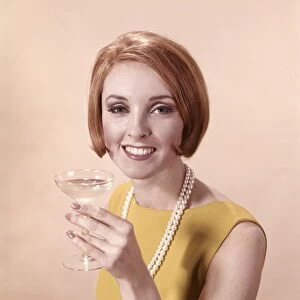 Portrait of glamorous woman in pearls holding cocktail