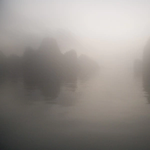 Rocks and water through mist at dawn