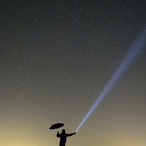 Silhouette of a man at night, in the rain, making signals with a flashlight