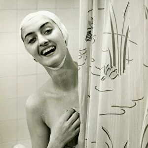 Smiling woman peeping behind shower curtain, (B&W), portrait