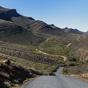 The winding road climbing up the remote and rugged wilderness area of the Cederberg mountains in the distance. Western Cape Province, South Africa