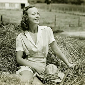 Woman sitting on haystack, (B&W), portrait